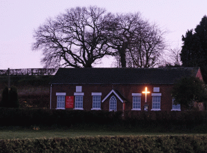 A picture of Ashley Methodist Church as seen at twilight from the A53 with it's illuminated cross for all to see.